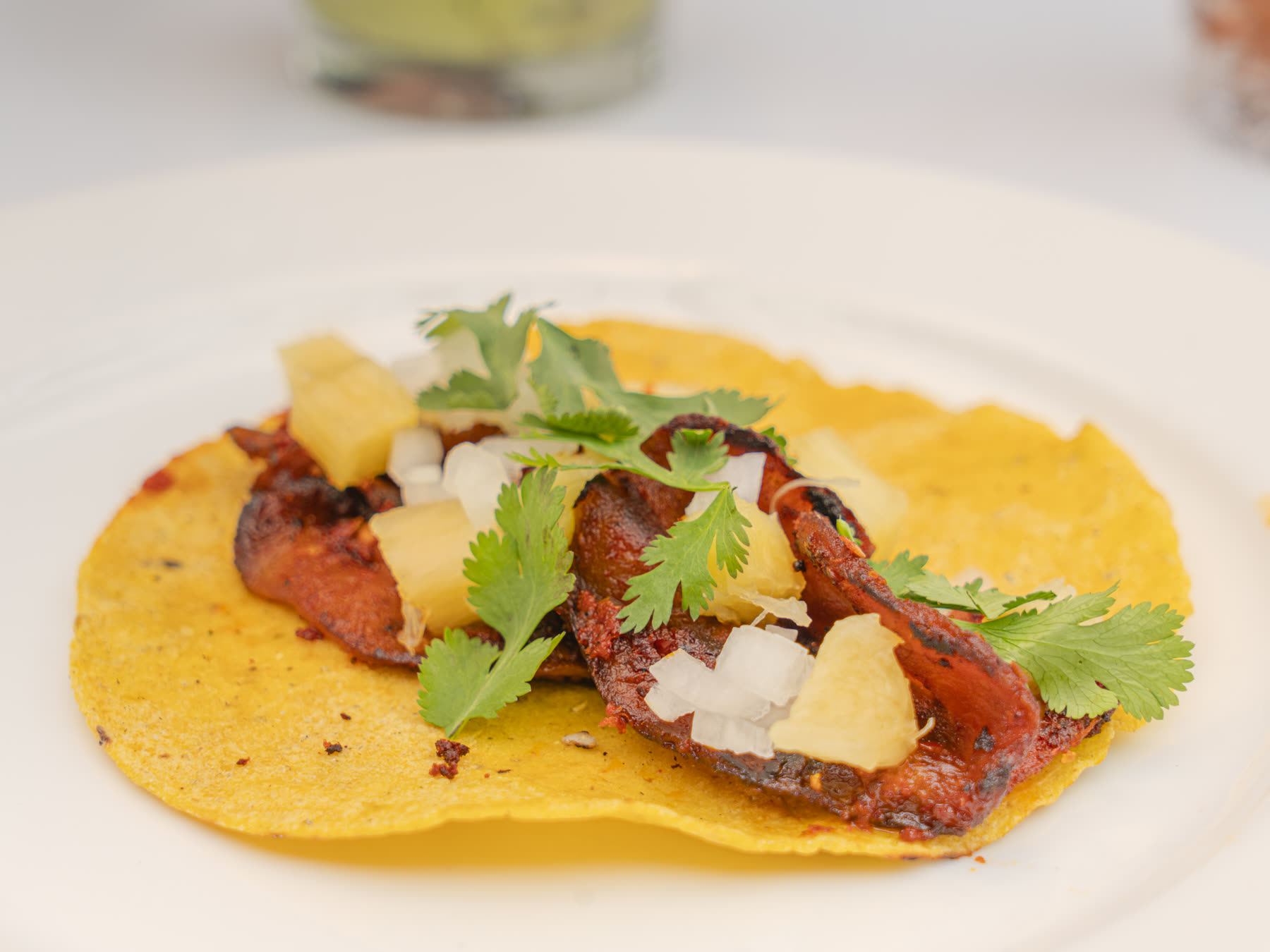 Al Pastor aubergine taco served on a yellow corn tortilla