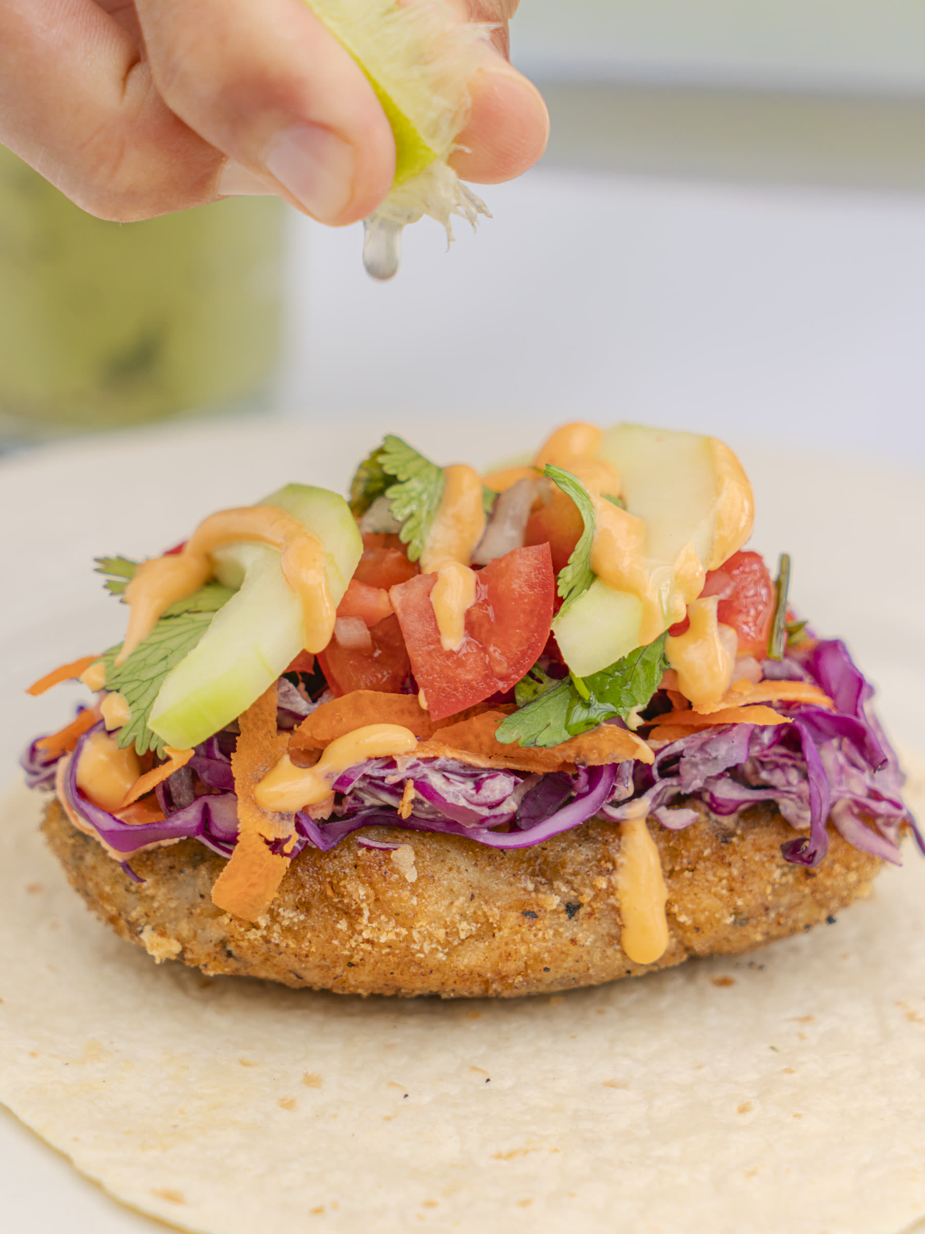 Close-up of crispy cauliflower taco with slaw and lime