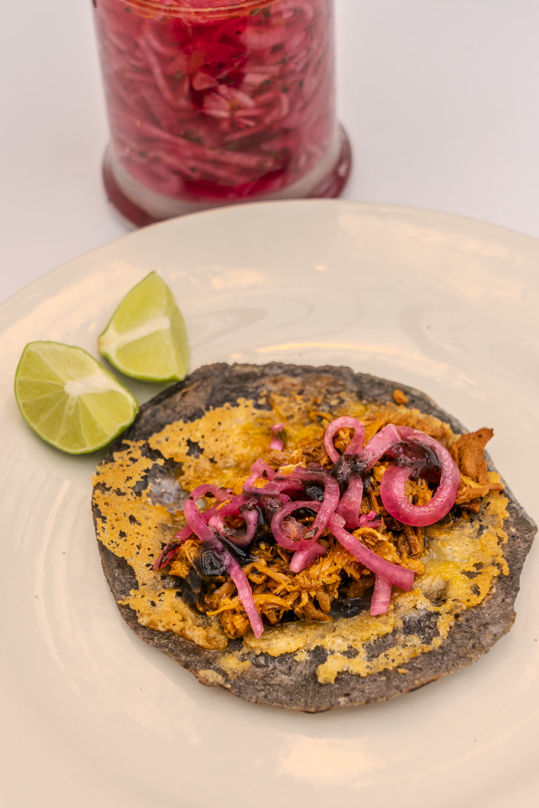 Pulled jackfruit taco on blue corn tortilla with pickled onions