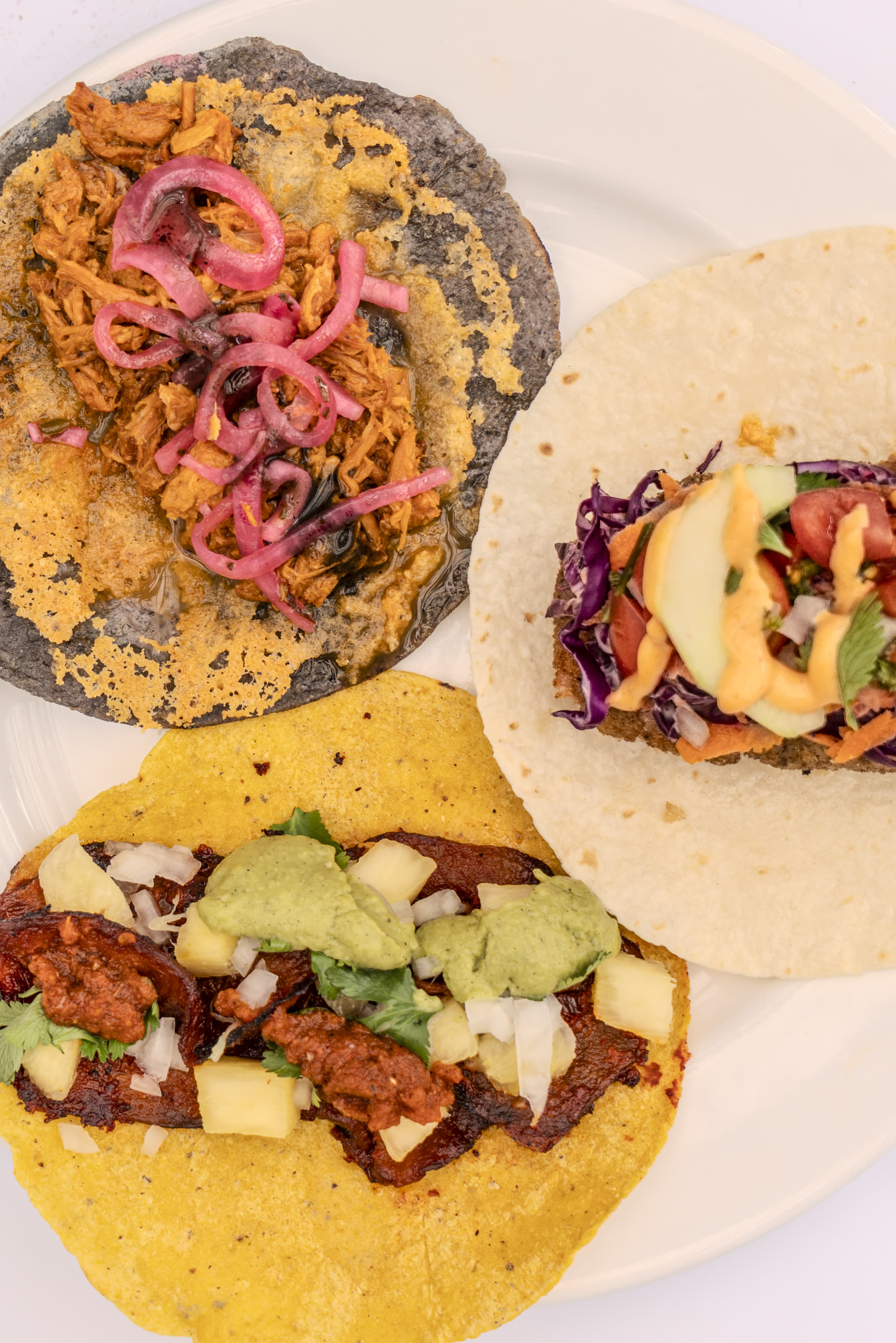 Three tacos arranged together on a plate