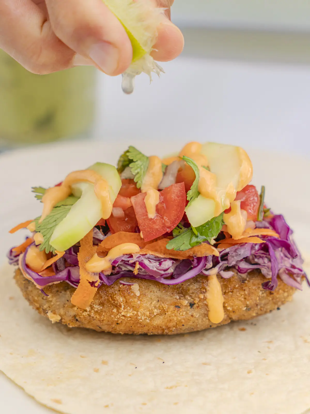 Close-up of crispy cauliflower taco with slaw and lime