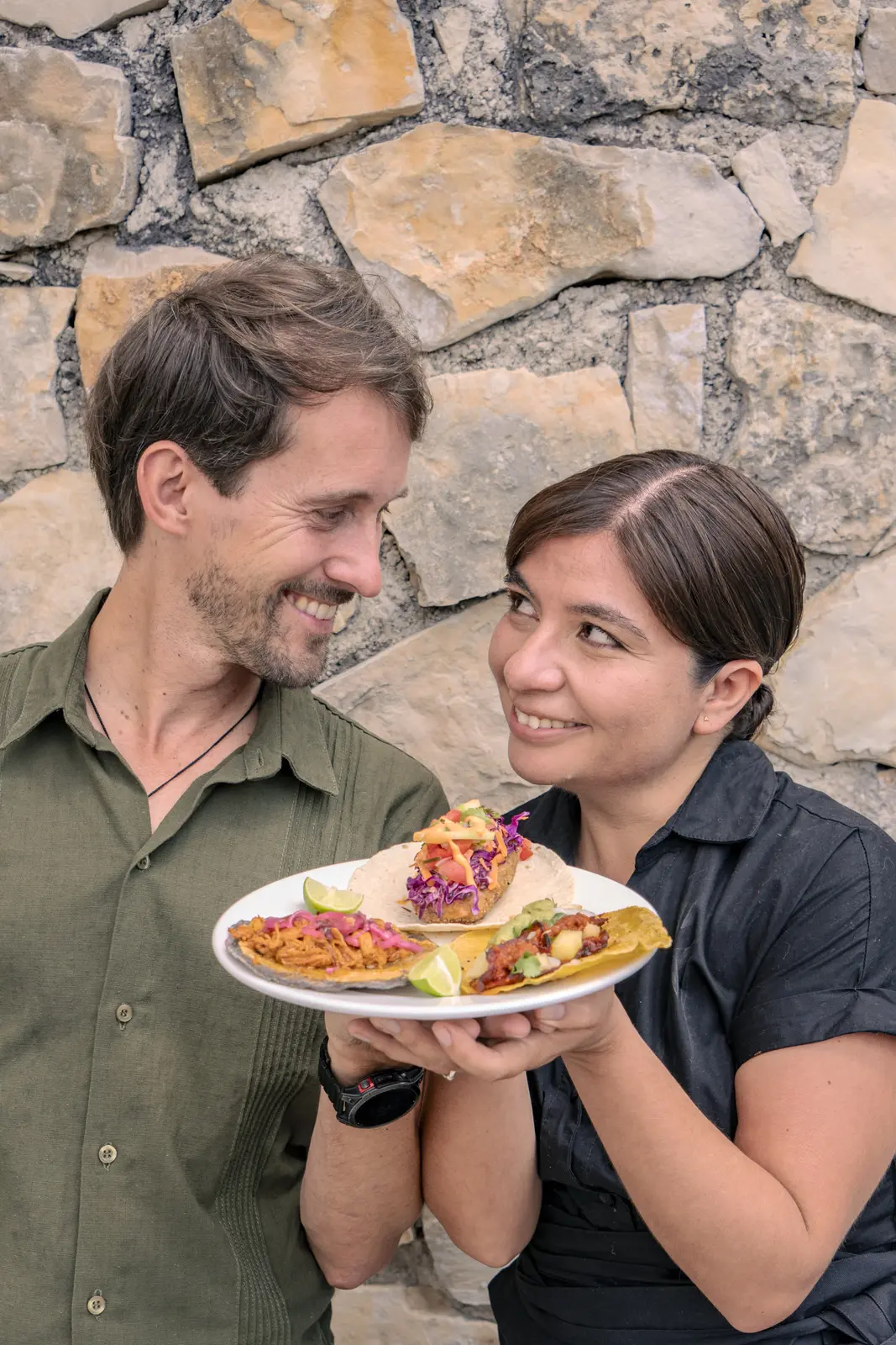 Mark and Paty smiling while holding a plate of tacos