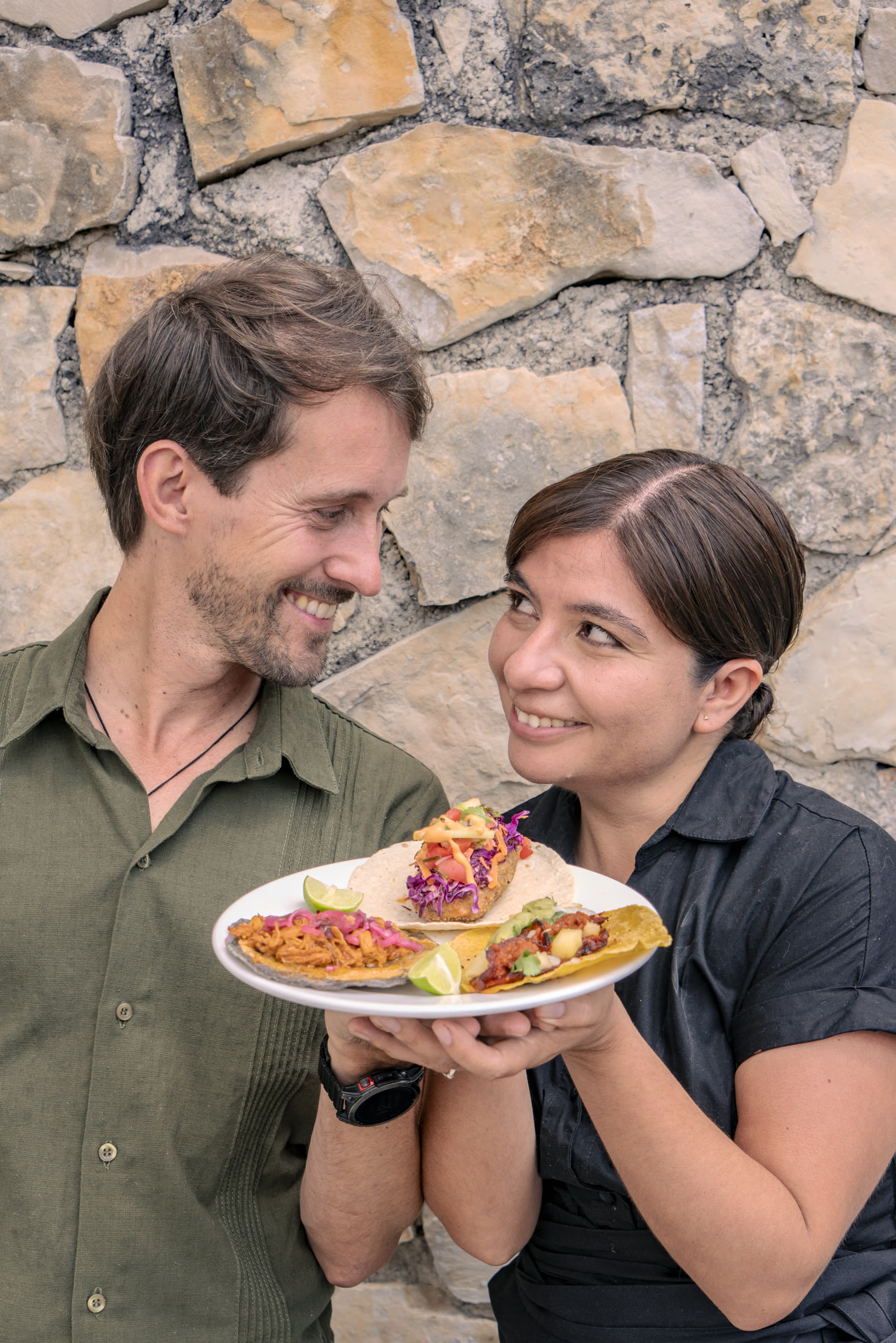 Mark and Paty smiling while holding a plate of tacos